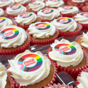Frosted cupcakes in red cases with a branded topper