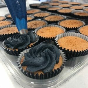 black frosting corporate cupcakes in production